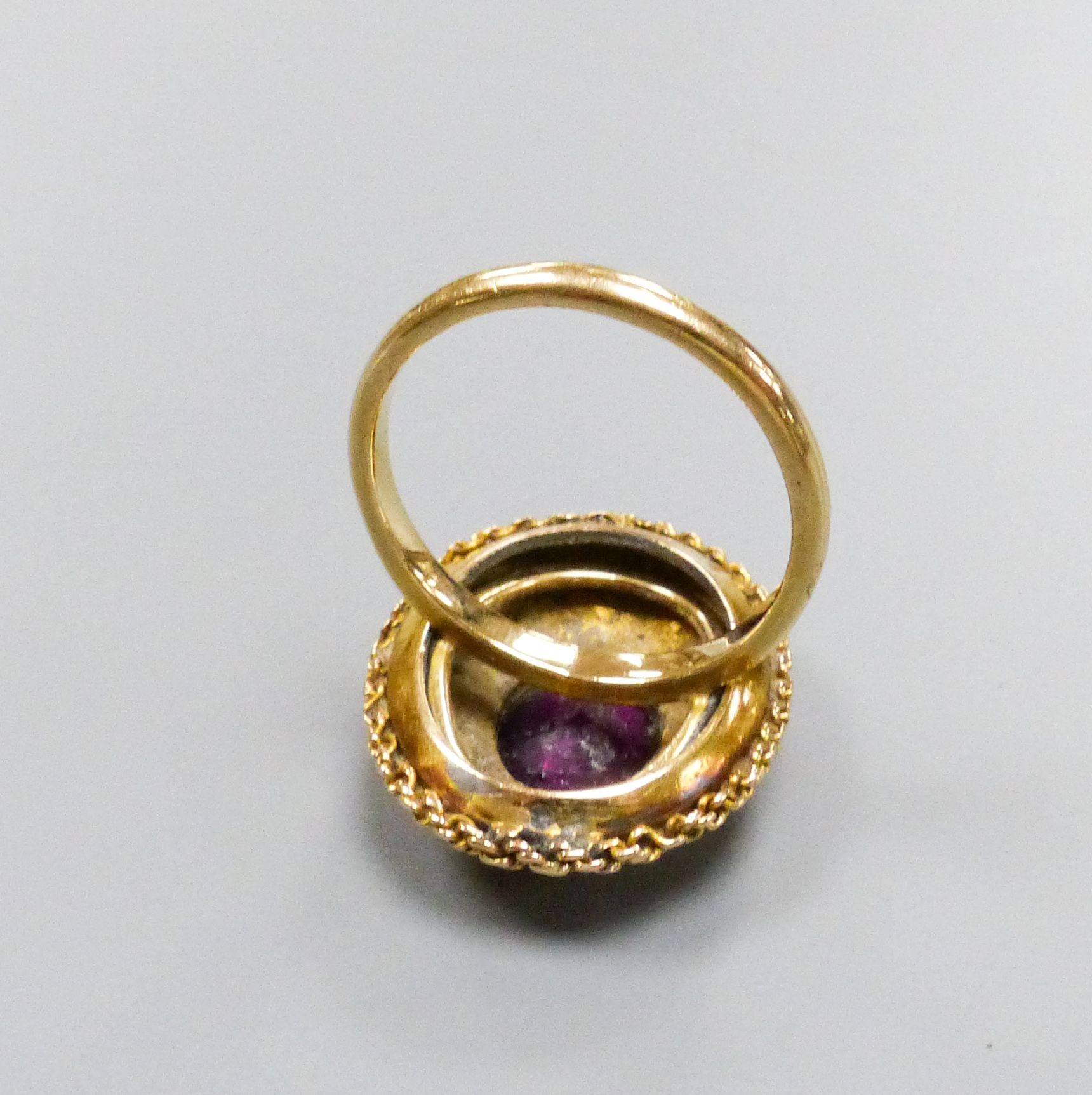 A 19th century engraved yellow metal and garnet set oval dress ring, with rope twist border (ring head loose), size N, gross weight 4.4 grams.